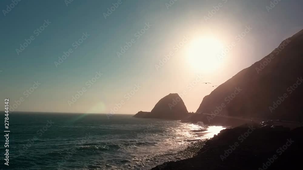 Sunset over Piru coastline with sun glare and seagulls flying Sunset over Piru coastline with sun glare and seagulls flying