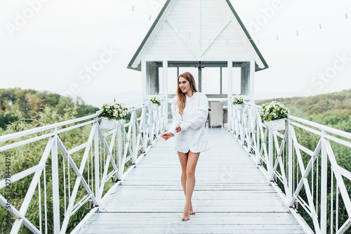 Morning of the bride, beautiful blonde woman in a man's shirt on the summer terrace. Wedding concept.