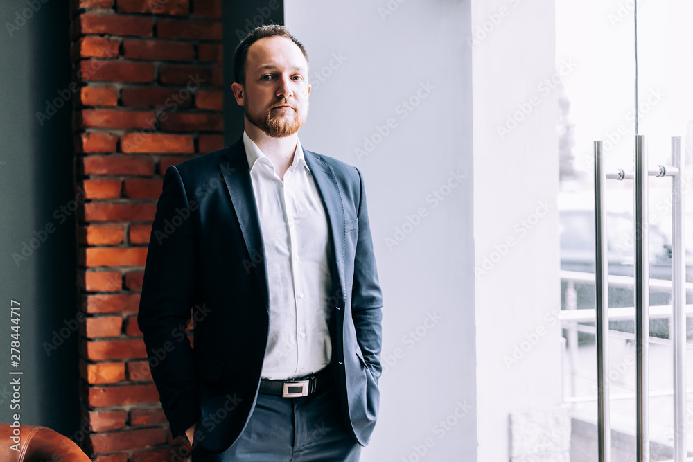 Successful. Businessman in a suit stands in an office and looks into the camera. Successful. Businessman in a suit stands in an office and looks into the camera.
