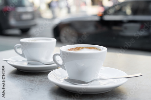 Two cups of cappuccino on a textured grey background. Street cafe. Close-up.