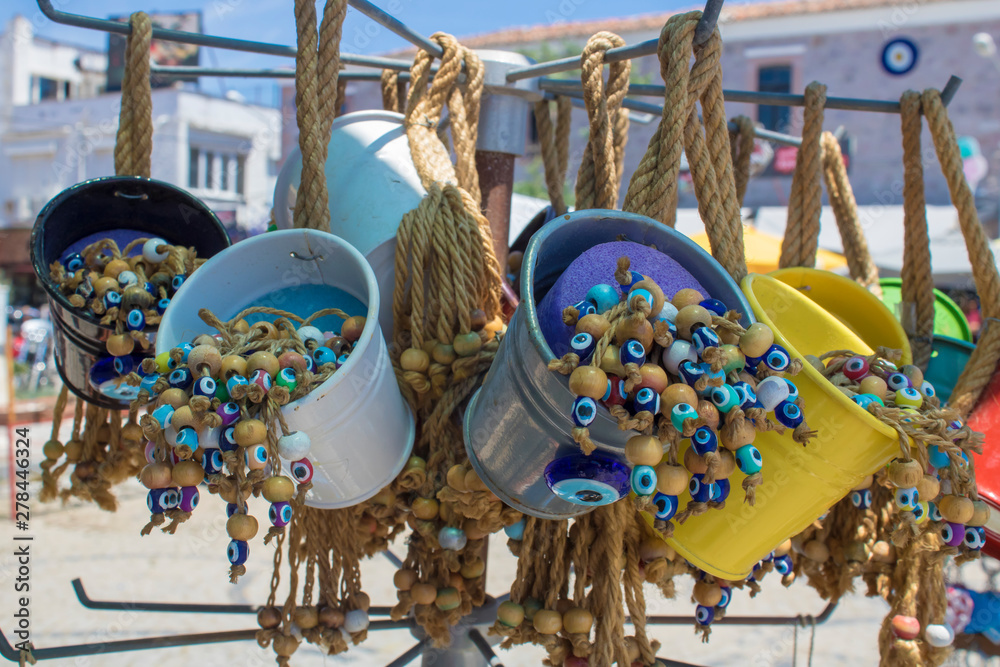 Decorative colorful small buckets sold in the store. Yellow color hanging with ropes. There are evil eye beads inside.