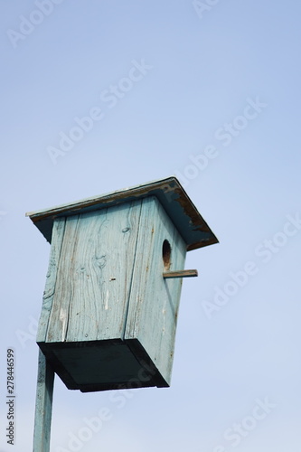 Blue wooden homemade birdhouse on the clear sky background
