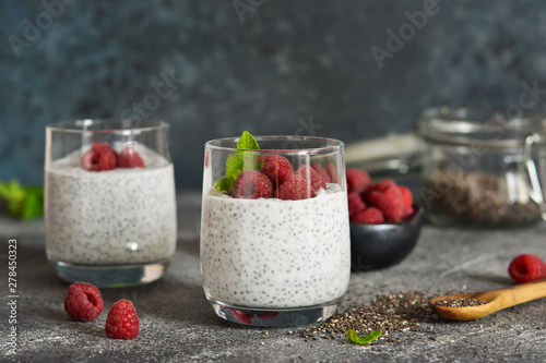 Chia pudding with yogurt and raspberries in a glass on concrete background