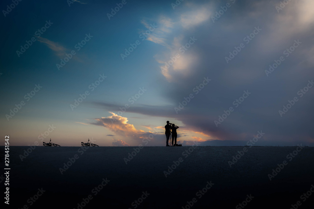 silhouette of people on top of mountain watching sunset