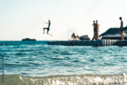 Floating platform in the sea, with teenagers having fun, out of focus
