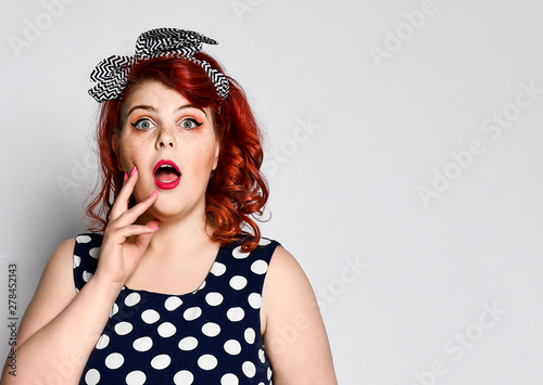 Pin up redhead woman portrait. Beautiful retro female in polka dot dress with red lips and manicure nails and old fashion hairstyle
