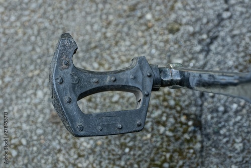 old broken pedal of black plastic and gray metal on a bicycle in the street