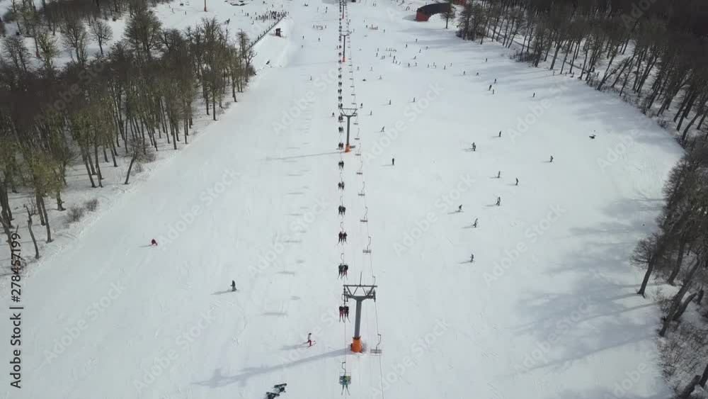 Centro invernal de esquí donde personas practican los deportes invernales. Montañas nevadas con pista de esquí. 