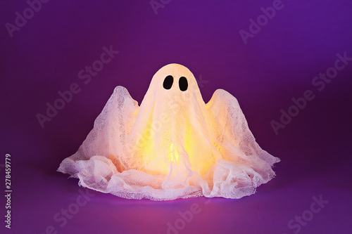 Halloween ghost of starch and gauze on ultraviolet background. Gift idea, decor Halloween. photo