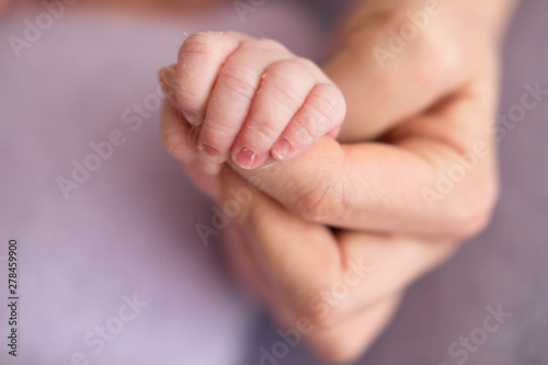 Newborn baby clenched fingers of his mother's finger