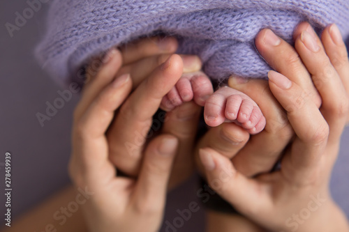 The legs of a newborn baby in the mother's arms. the legs of a newborn baby in his hands . baby's feet. baby feet on background