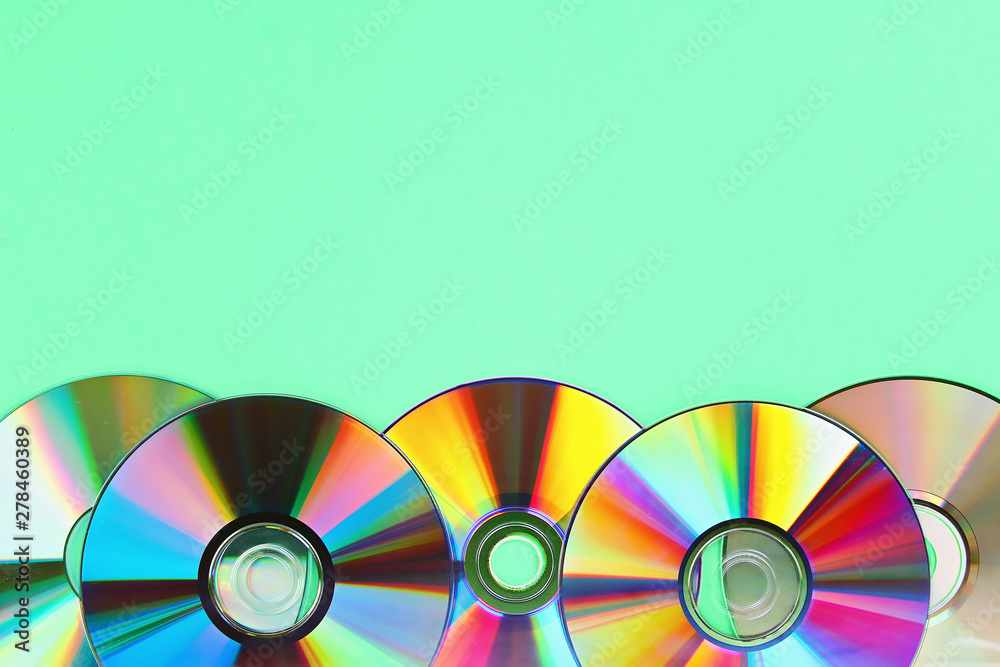 Piles of old and dirty CDs,DVD on pastel mint background. Used and dusty disk with copy space Piles of old and dirty CDs,DVD on pastel mint background. Used and dusty disk with copy space