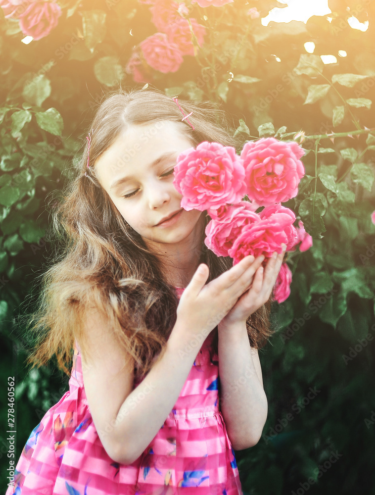 Fototapeta premium Beautiful little girl posing with roses outdoors.