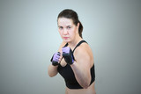 a woman practices taekwondo and stands in a boxing pose with a clenched fist. Isolated on gray studio background. 