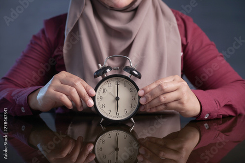 Muslim Woman Holding Clock Pointing at Six O'Clock