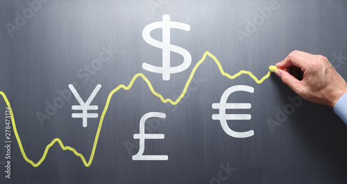 Drawing graph of exchange rate on chalkboard. Exchange rate fluctuations concept. photo