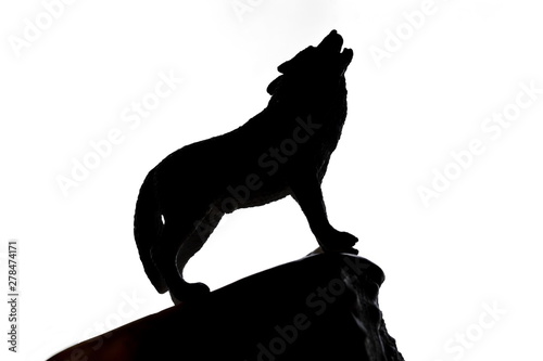 Black silhouette of a wolf with its muzzle raised up on edge of top of cliff howl on white background. Isolated. Horizontal frame