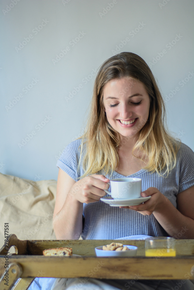 Young woman in bed eating breakfast Young woman in bed eating breakfast