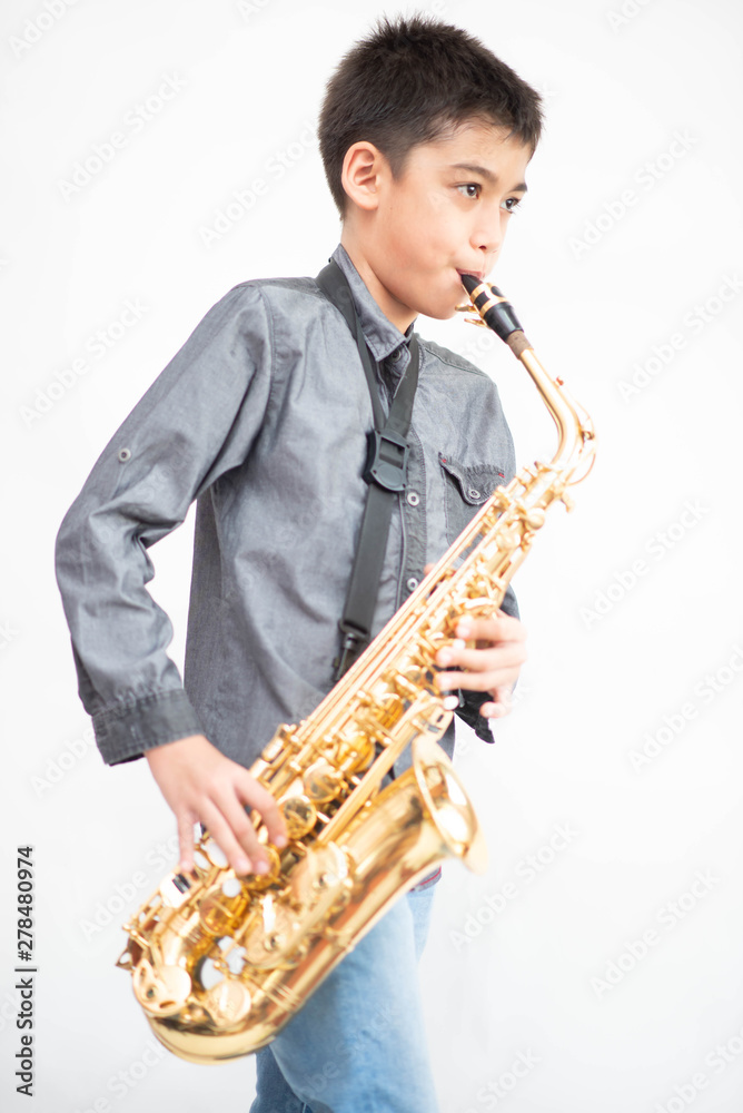 Naklejka premium Little asian musician boy playing saxophone instrument