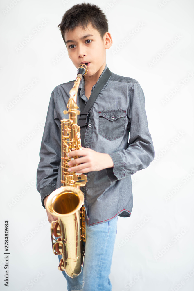 Fototapeta premium Little asian musician boy playing saxophone instrument