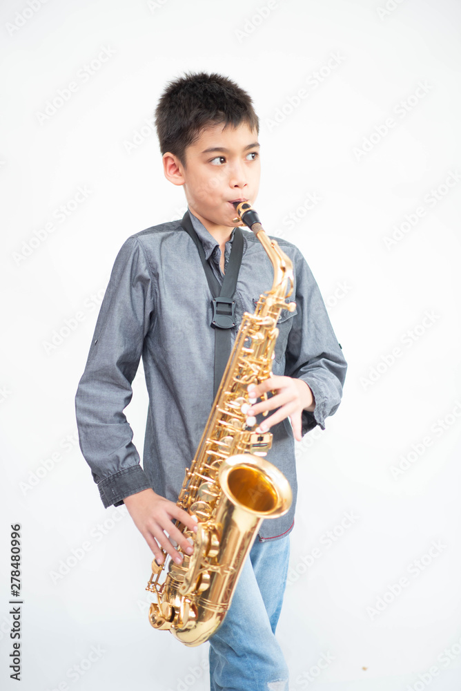 Naklejka premium Little asian musician boy playing saxophone instrument