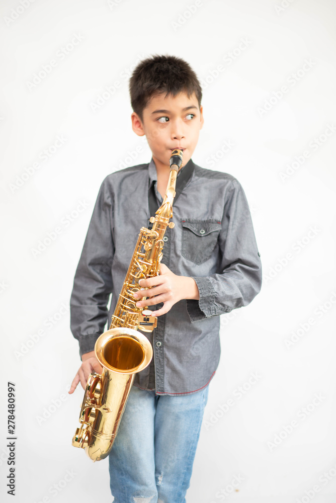 Obraz premium Little asian musician boy playing saxophone instrument