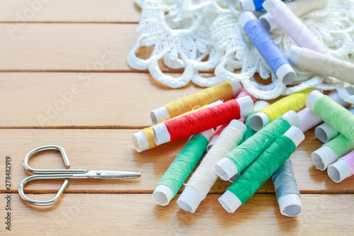 Colorful threads and beautiful white french lace on wooden table.