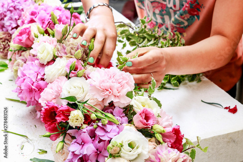 Woman making floral arrangement with carnation  eustoma and hortensia flowers.