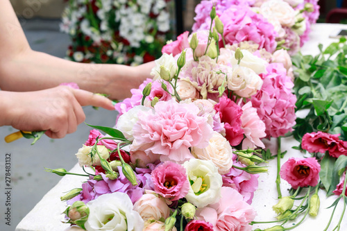 Woman making floral arrangement with carnation  eustoma and hortensia flowers.