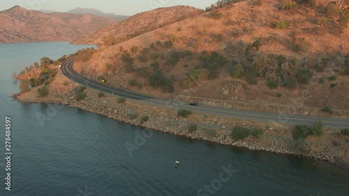 Aerial Drone Tracking Shot of a Car Driving next to a Mountain Lake During Sunset (Lake Kaweah, Visalia, California)