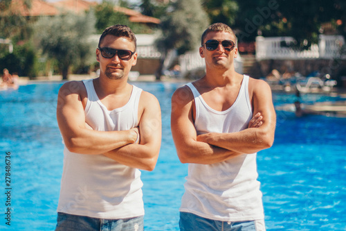 the concept of recreation, tourism - two smiling inflated men with glasses having fun by the pool © aaalll3110