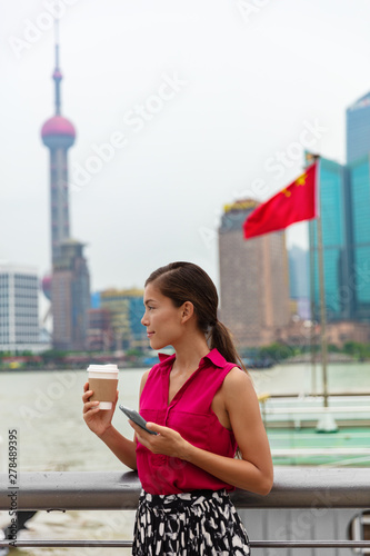 China phone Asian professional woman using cellphone during commute to work by the Bund river in Shanghai, chinese lifestyle.