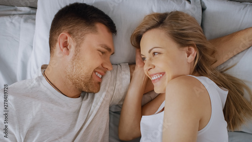 Happy Young Couple Cuddling Together in the Bed, Young Woman is Pregnant and Loving Partner Touches and Caresses Her Tenderly. Top View Shot.