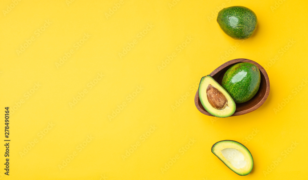 organic avocados half cut with seed and whole fruit in wood bowl on yellow table background.Healthy super foods for diet.Fresh vegetable from farm.keto food ingredients.top view banner mock up. organic avocados half cut with seed and whole fruit in wood bowl on yellow table background.Healthy super foods for diet.Fresh vegetable from farm.keto food ingredients.top view banner mock up.