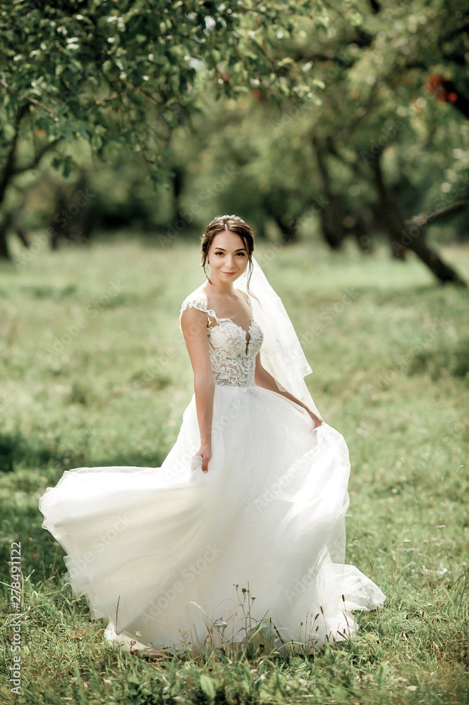 bride posing in a green park; girl in a white dress on a background of green bride posing in a green park; girl in a white dress on a background of green