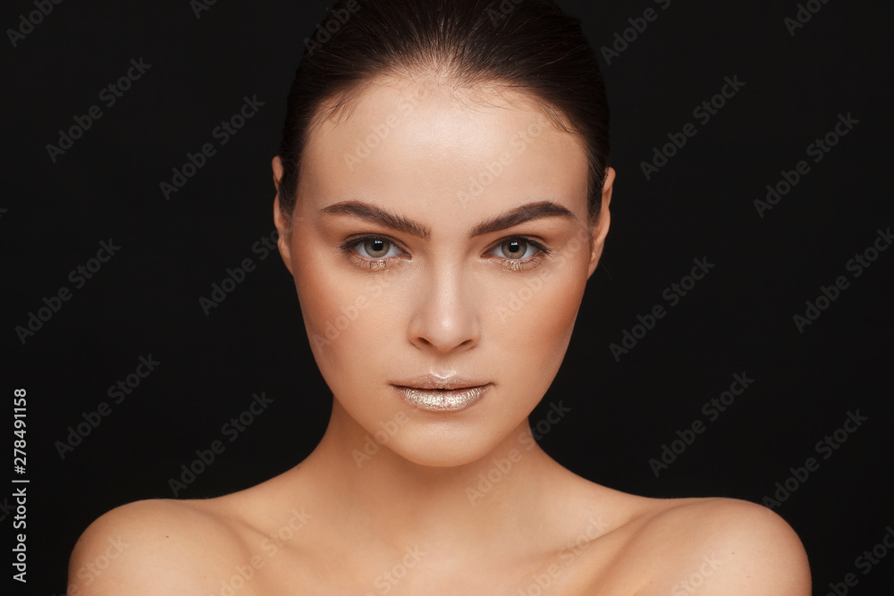 Portrait of a beautiful woman with collected hair and bare shoulders on a black background Portrait of a beautiful woman with collected hair and bare shoulders on a black background