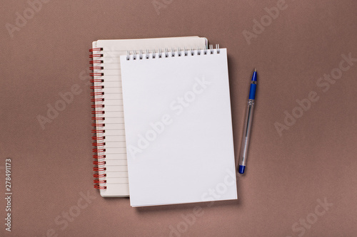 school notepad and pen on the brown desk. spiral notepad on a table. flatlay