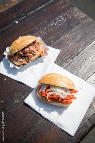 Fischbrötchen mit Nordseekrabben und Alaska Seelachs draußen auf Fischmarkt Holztisch als schneller regionaler Imbiss photo