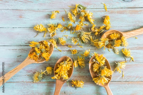 dried calendula flowers in wooden spoons on a vintage table. top view