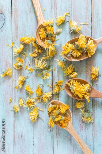 dried calendula flowers in wooden spoons on a vintage table. top view