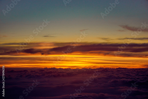 orange sky and clouds from an airplane window during an evening flight.