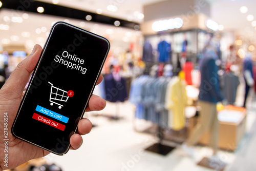 Person using smartphone buying and making a payment digitally via application on blur shopping mall background - internet online home shopping concept