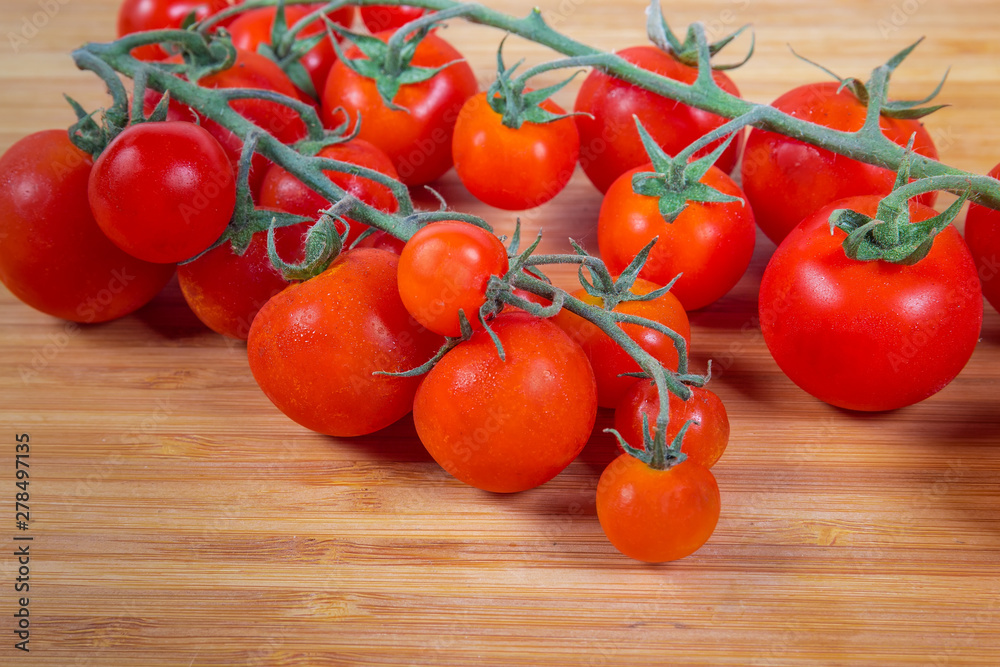Cherry tomato clusters on the bamboo cutting board close-up Cherry tomato clusters on the bamboo cutting board close-up