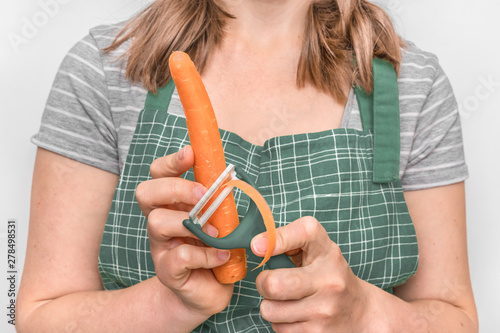 Woman peeling a carrot using food peeler