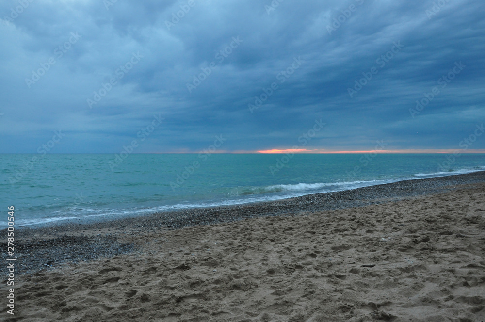 Sunset against a stormy sky and blue sea