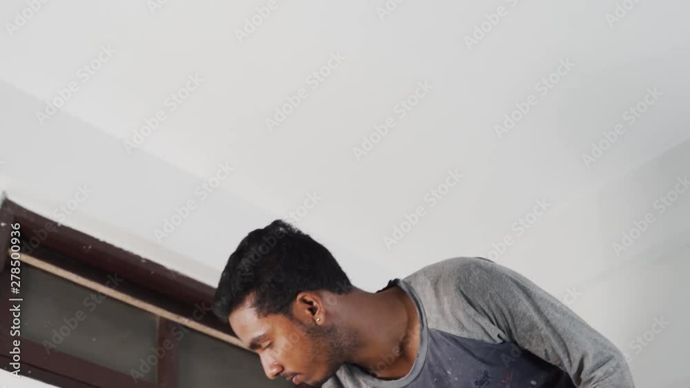 A wall being decorated with white paint by a young man A wall being decorated with white paint by a young man