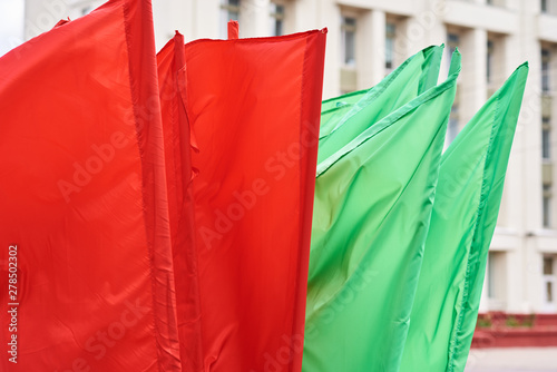 Red and green flags on a flagpoles flying in the wind