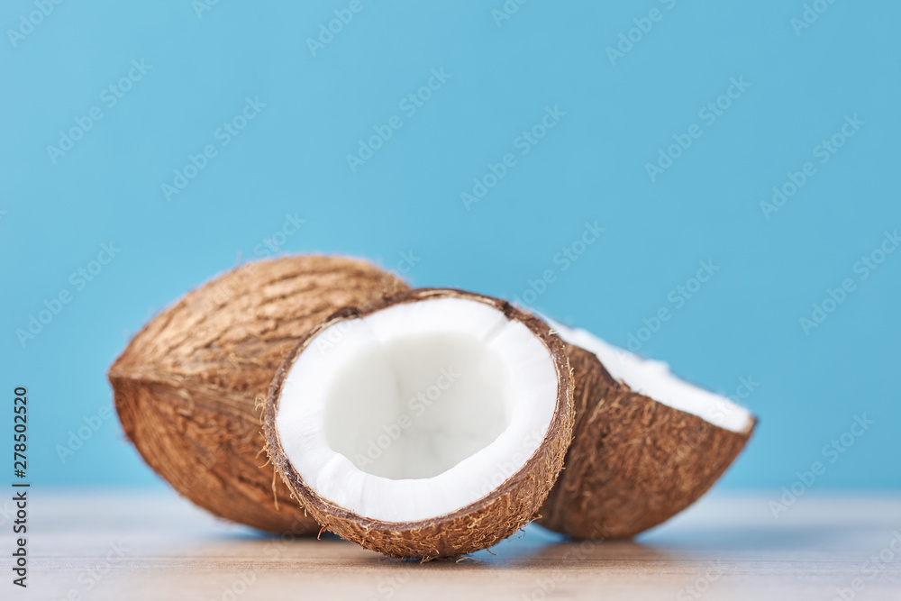 Full Coconut and cracked half on a blue background, close up Full Coconut and cracked half on a blue background, close up