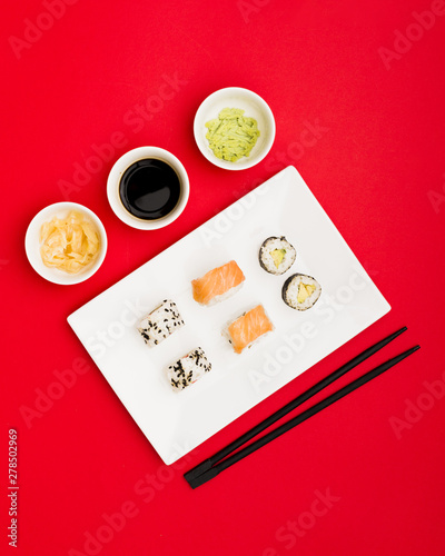 Japanese sushi with soy sauce; ginger and wasabi over red backdrop