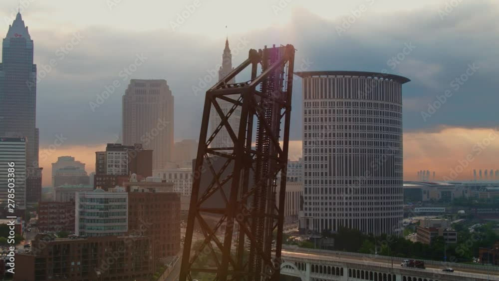 Aerial drone orbit around old lift bridge during beautiful sunrise with downtown Cleveland, Ohio skyline in background Aerial drone orbit around old lift bridge during beautiful sunrise with downtown Cleveland, Ohio skyline in background